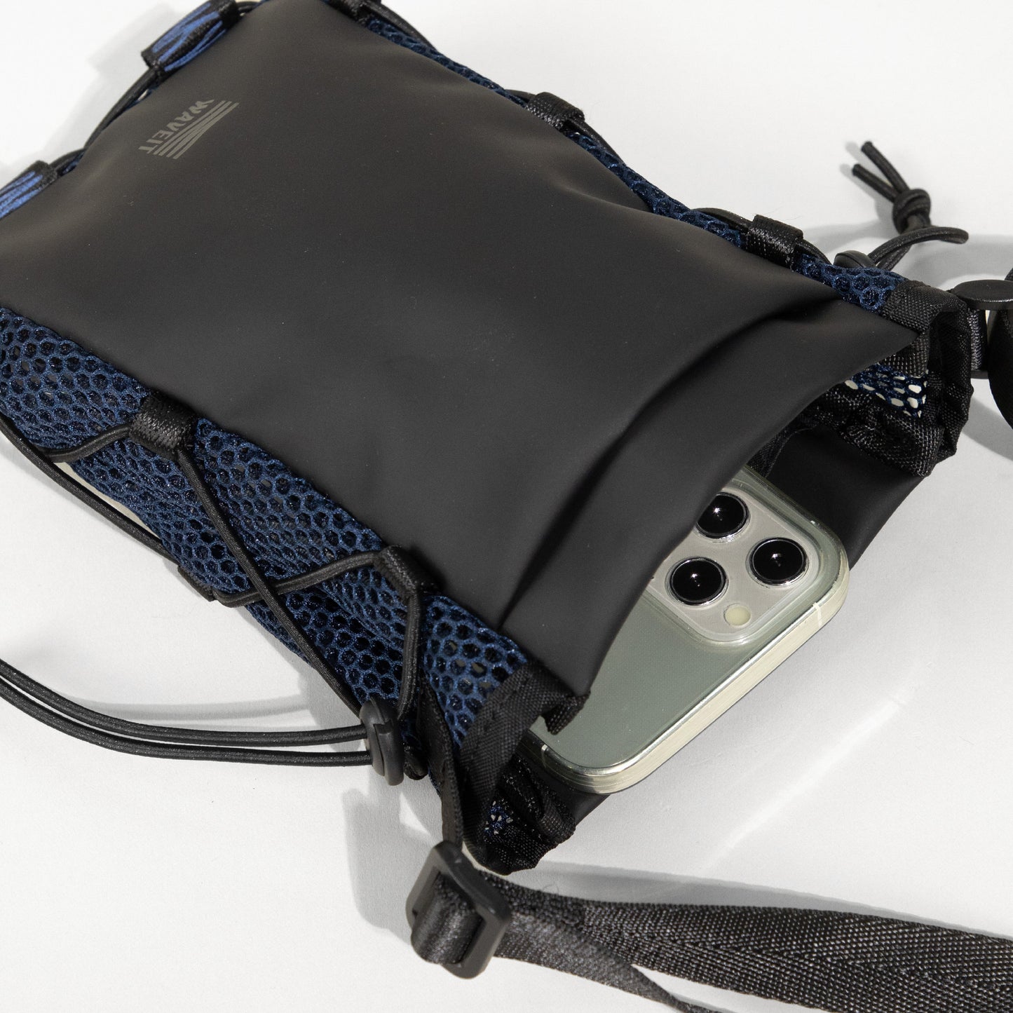 Close-up view of the WAVEIT crossbody bag in black with a mesh exterior pocket holding a smartphone, showing the detailed texture and stitching.