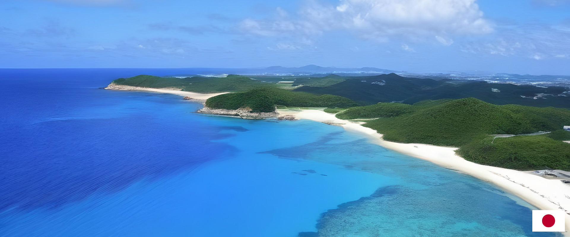 Panoramic view of a pristine beach and coastline with clear blue waters and lush green hills in the background, showcasing the natural beauty of coastal landscapes.